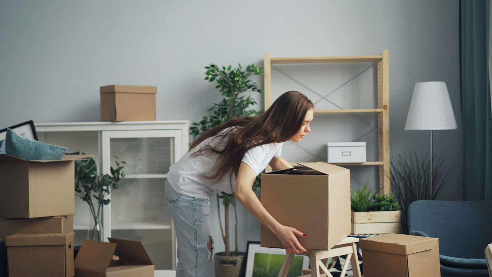 a woman moving boxes in a living room